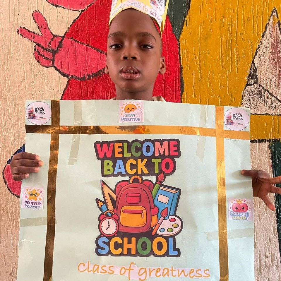 Smiling pupil with a Welcome Back to School sign