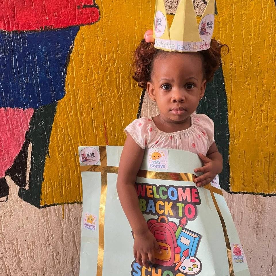 Nursery child holding a Welcome Back to School board
